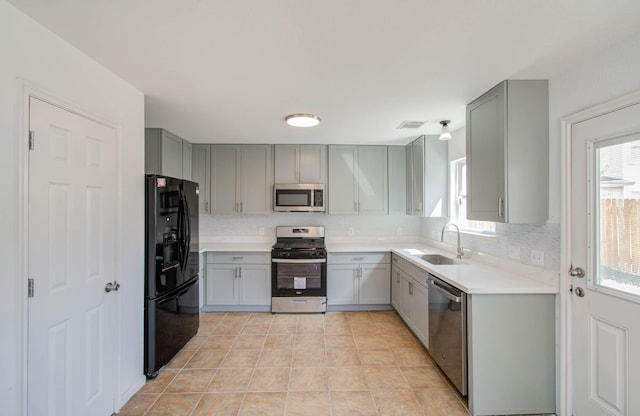 kitchen featuring gray cabinetry, sink, tasteful backsplash, light tile patterned flooring, and appliances with stainless steel finishes