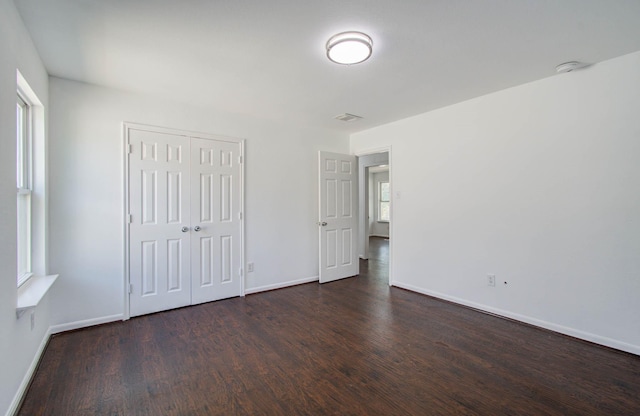 unfurnished bedroom with dark hardwood / wood-style floors and a closet