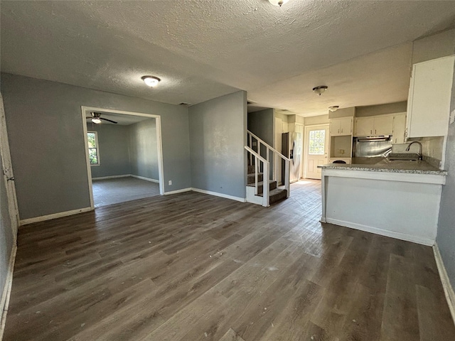 interior space featuring kitchen peninsula, stainless steel refrigerator with ice dispenser, dark wood-type flooring, white cabinetry, and fridge