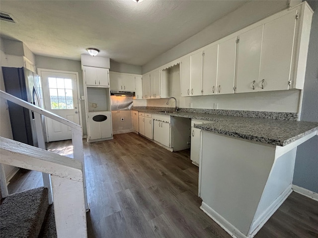 kitchen with kitchen peninsula, sink, dark hardwood / wood-style floors, white cabinetry, and stainless steel refrigerator