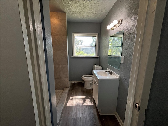 bathroom featuring vanity, a shower, hardwood / wood-style flooring, toilet, and a textured ceiling