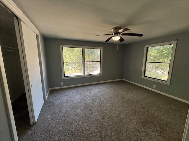 unfurnished bedroom featuring a closet, dark carpet, and ceiling fan