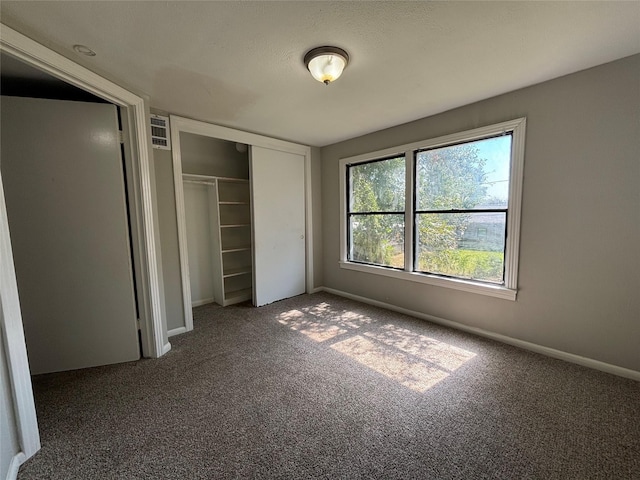 unfurnished bedroom featuring dark colored carpet and a closet