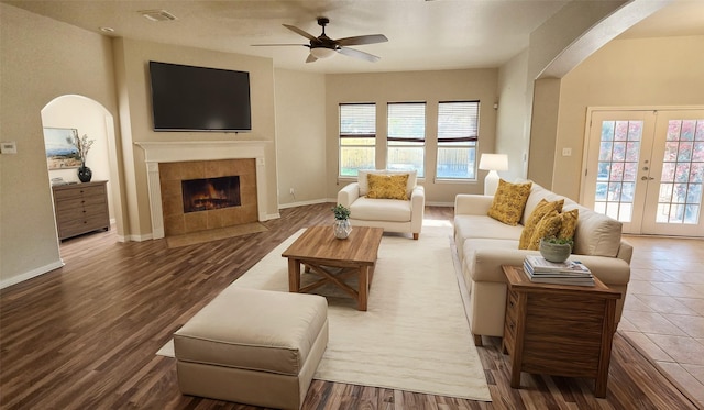 living room with hardwood / wood-style flooring, ceiling fan, a fireplace, and french doors