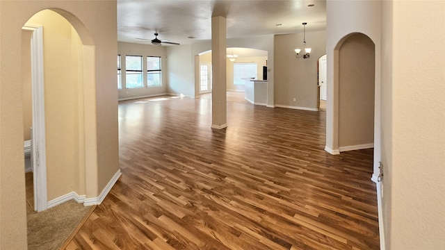 empty room with dark hardwood / wood-style floors and ceiling fan with notable chandelier