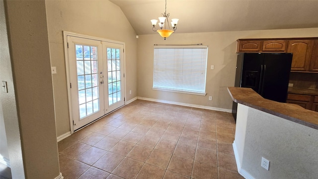 unfurnished dining area with french doors, light tile patterned floors, vaulted ceiling, and a notable chandelier