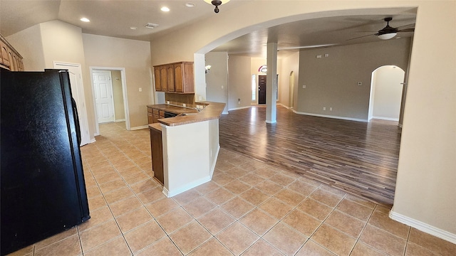 kitchen with kitchen peninsula, ceiling fan, and black refrigerator