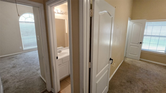 corridor featuring light carpet, a wealth of natural light, and sink