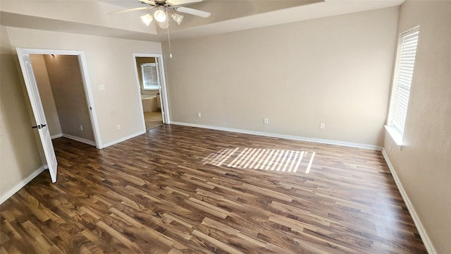 empty room with a tray ceiling, ceiling fan, and dark hardwood / wood-style floors