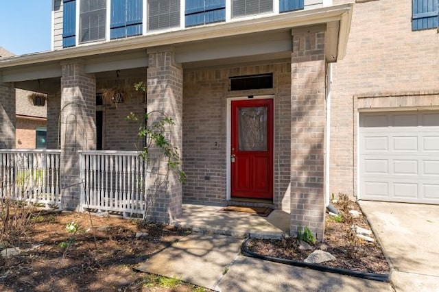 doorway to property with a garage, a porch, and brick siding