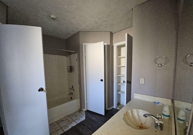 bathroom with a textured ceiling, vanity, and  shower combination