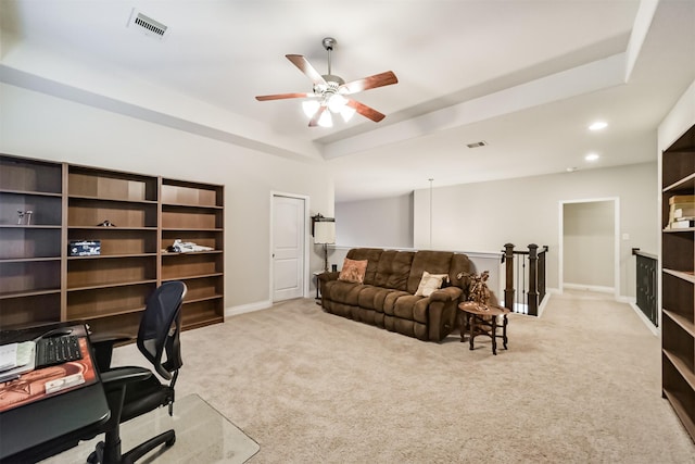 carpeted office with a raised ceiling and ceiling fan