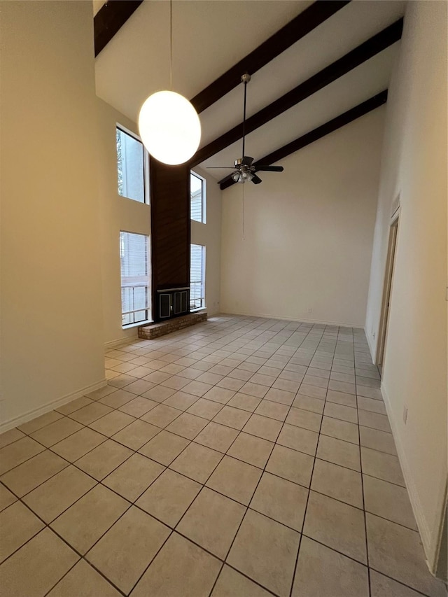 unfurnished living room featuring ceiling fan, beamed ceiling, a high ceiling, and light tile patterned floors