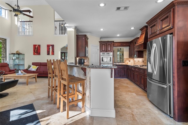 kitchen featuring kitchen peninsula, decorative backsplash, a kitchen bar, premium range hood, and stainless steel appliances