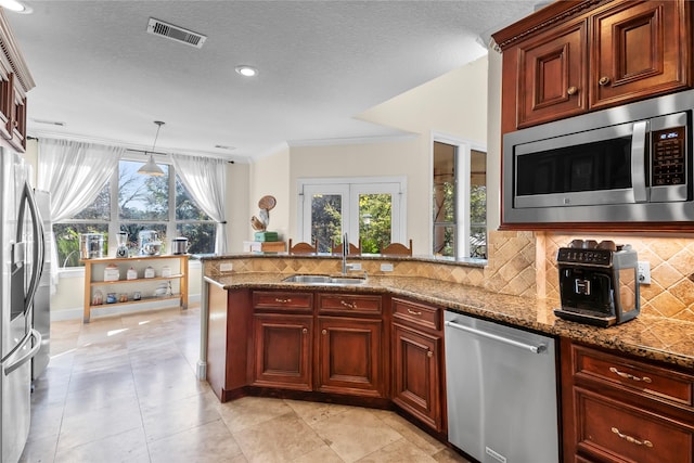 kitchen with pendant lighting, crown molding, sink, light stone countertops, and stainless steel appliances