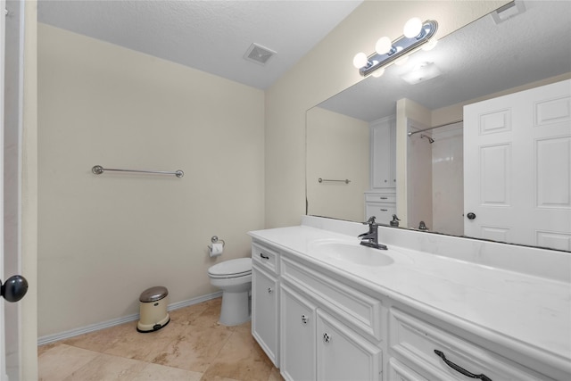 bathroom with a textured ceiling, vanity, and toilet