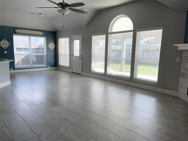 tiled empty room with lofted ceiling, a fireplace, ceiling fan, and a healthy amount of sunlight