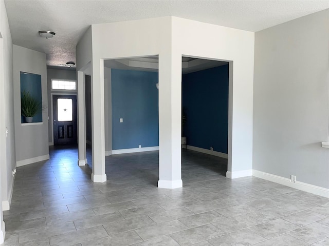 tiled empty room with a textured ceiling