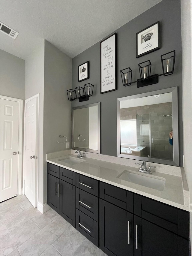 bathroom with tile patterned flooring, vanity, a textured ceiling, and plus walk in shower