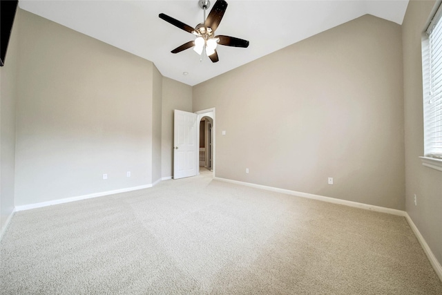 carpeted empty room with a wealth of natural light, ceiling fan, and vaulted ceiling