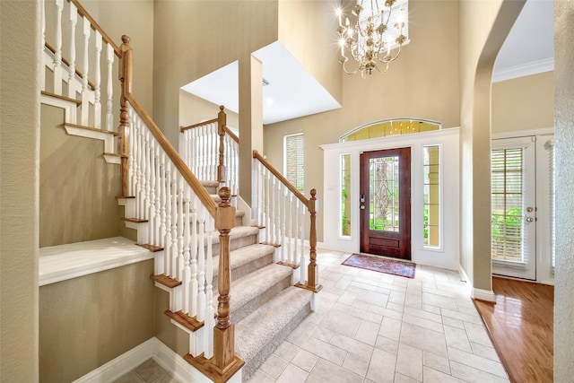 foyer featuring a chandelier, a high ceiling, and crown molding