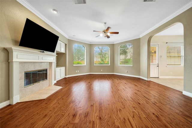 unfurnished living room featuring a tile fireplace, ceiling fan, hardwood / wood-style floors, and ornamental molding