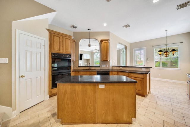 kitchen with pendant lighting, black appliances, sink, a kitchen island, and kitchen peninsula