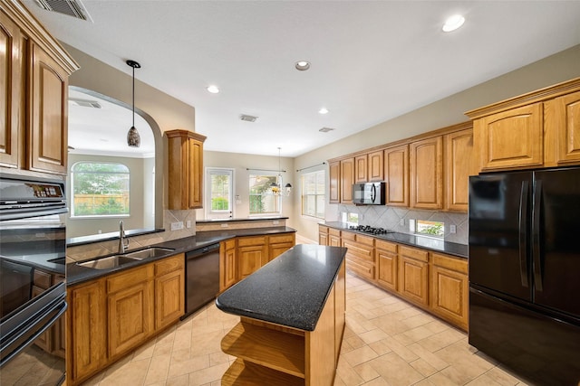 kitchen featuring pendant lighting, sink, a kitchen island, and black appliances