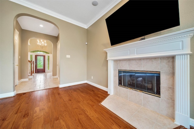 unfurnished living room featuring a fireplace, light wood-type flooring, an inviting chandelier, and crown molding