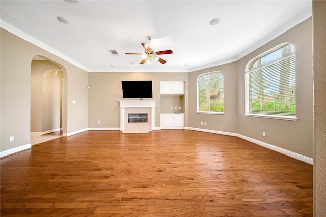 unfurnished living room featuring a fireplace, hardwood / wood-style floors, ceiling fan, and ornamental molding