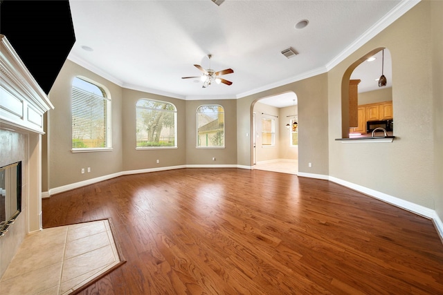 unfurnished living room featuring ceiling fan, crown molding, a premium fireplace, and light hardwood / wood-style flooring