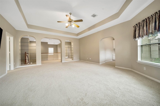 carpeted spare room with ceiling fan and a raised ceiling