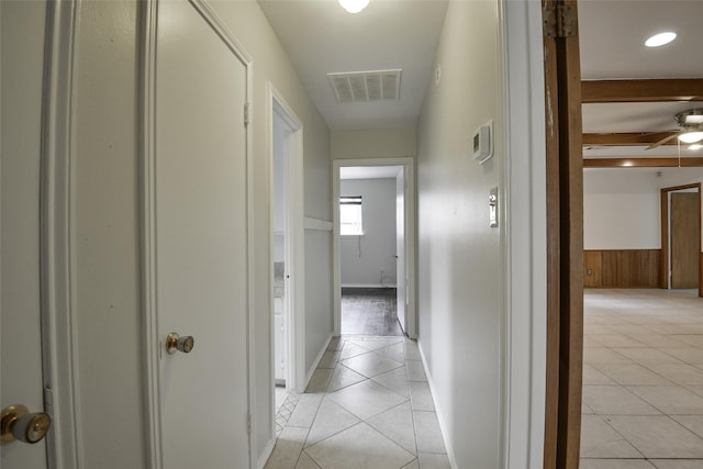 hallway with wood walls and light tile patterned floors