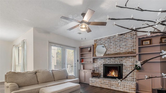 living room featuring ceiling fan, a fireplace, and dark wood-type flooring