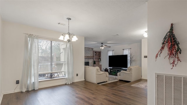 unfurnished living room featuring ceiling fan with notable chandelier, dark hardwood / wood-style flooring, and a fireplace