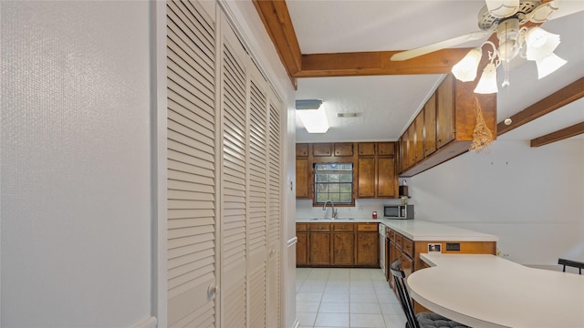 kitchen with light tile patterned flooring, beam ceiling, ceiling fan, and sink