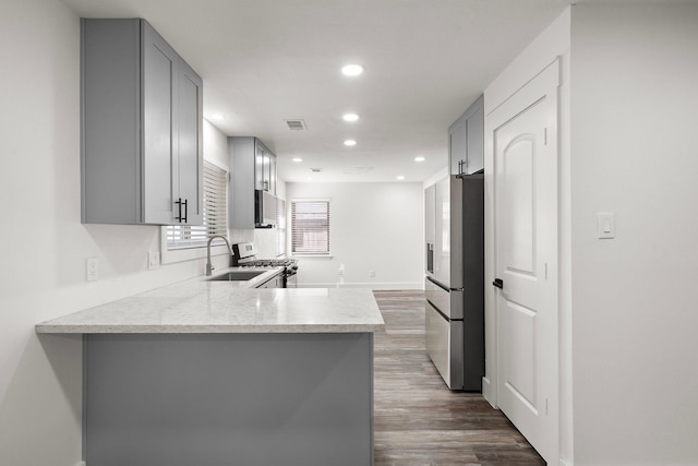 kitchen with sink, white gas stove, stainless steel fridge with ice dispenser, kitchen peninsula, and gray cabinets