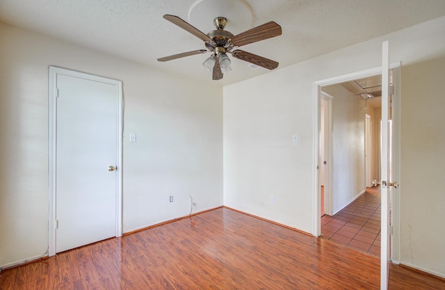 unfurnished bedroom featuring ceiling fan, hardwood / wood-style floors, and a textured ceiling