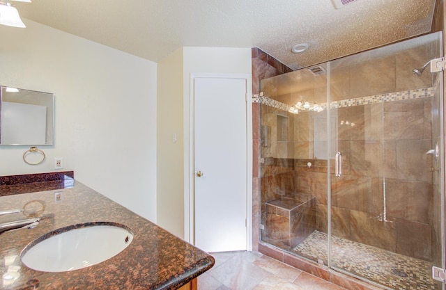 bathroom featuring vanity, a shower with shower door, and a textured ceiling