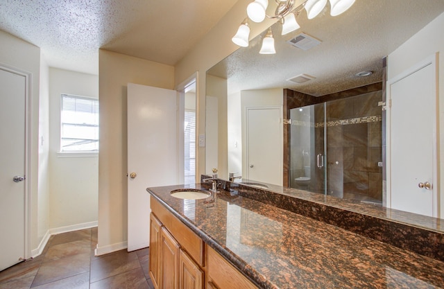 bathroom featuring vanity, a shower with door, tile patterned floors, toilet, and a textured ceiling