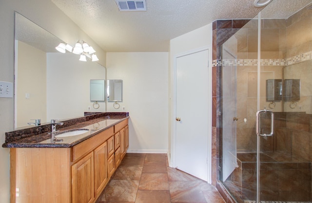 bathroom with vanity, a textured ceiling, and walk in shower