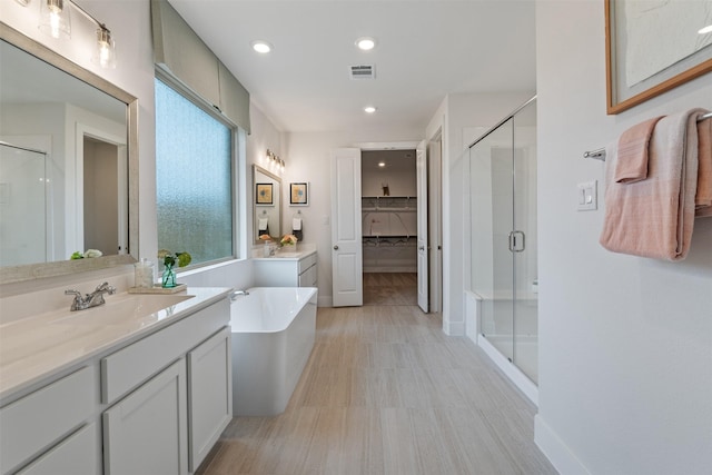 bathroom featuring plus walk in shower, hardwood / wood-style floors, and vanity