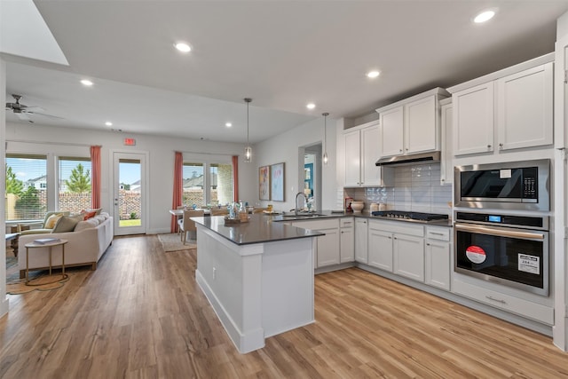 kitchen featuring sink, hanging light fixtures, kitchen peninsula, white cabinets, and appliances with stainless steel finishes