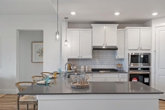 kitchen with appliances with stainless steel finishes, backsplash, sink, white cabinetry, and hanging light fixtures