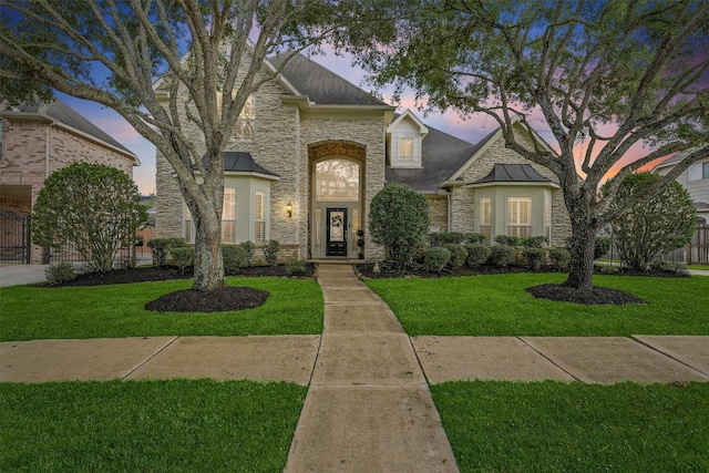 french country inspired facade featuring a yard