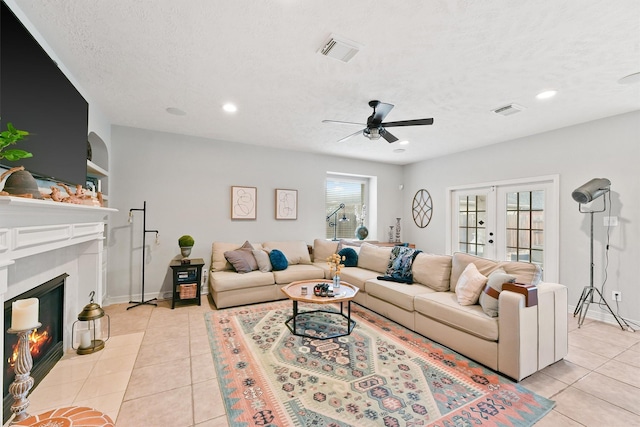 living room with light tile patterned floors, a textured ceiling, french doors, and ceiling fan