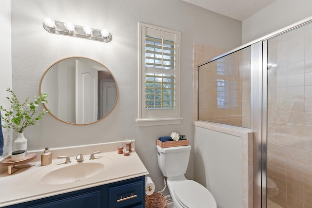 bathroom with a textured ceiling, vanity, an enclosed shower, and toilet