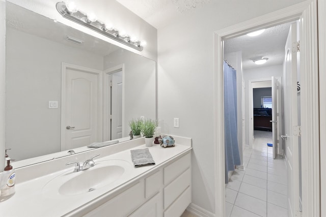 bathroom featuring tile patterned flooring, vanity, and a textured ceiling