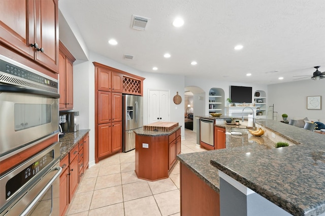 kitchen with ceiling fan, sink, a center island with sink, light tile patterned floors, and appliances with stainless steel finishes