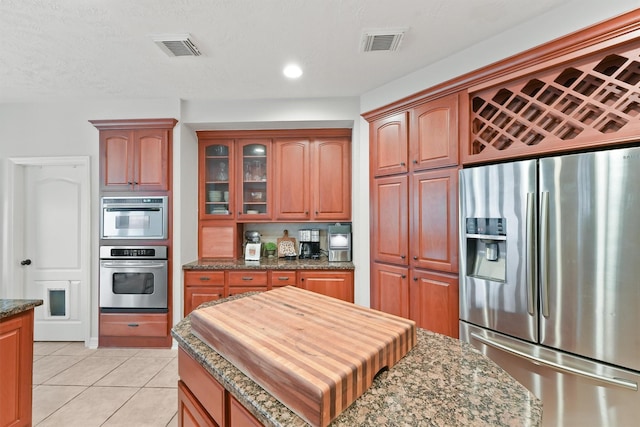 kitchen featuring dark stone countertops, stainless steel fridge with ice dispenser, and light tile patterned floors